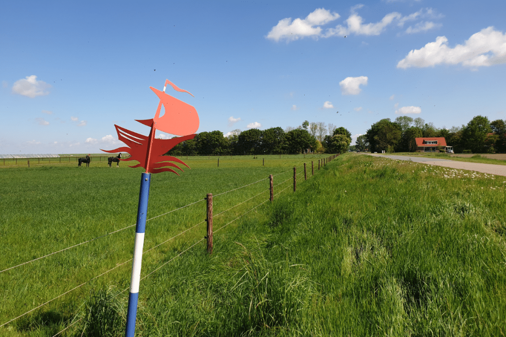 Blauw-witte paal met een rood scheepje erop in de Flevopolder